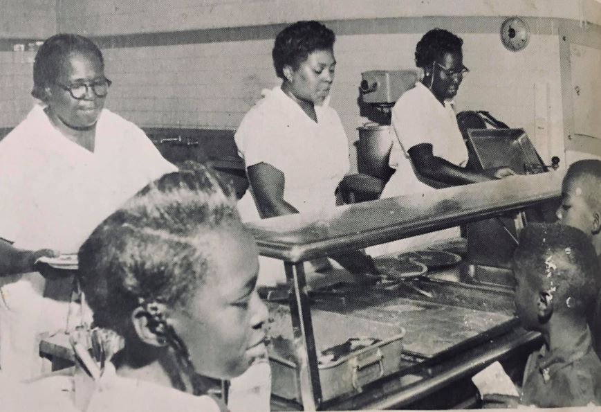 Lunch room staff members serving food to students.