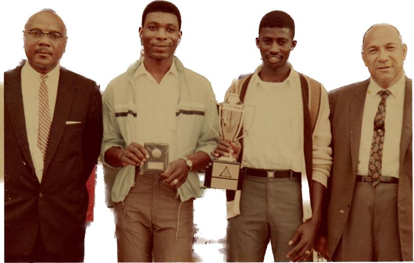 4 men posing for the camera, one holding a plaque, another holding a trophy