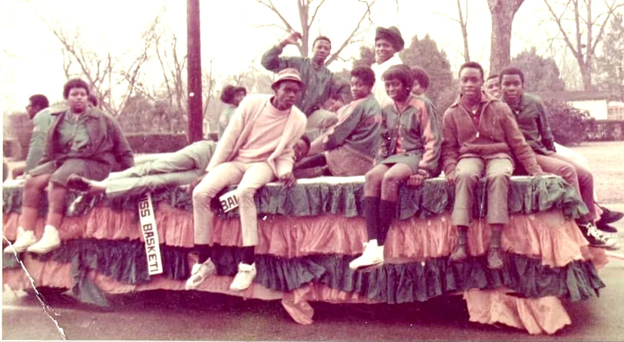 multiple teenagers sit on a homecoming float, posing for the camera